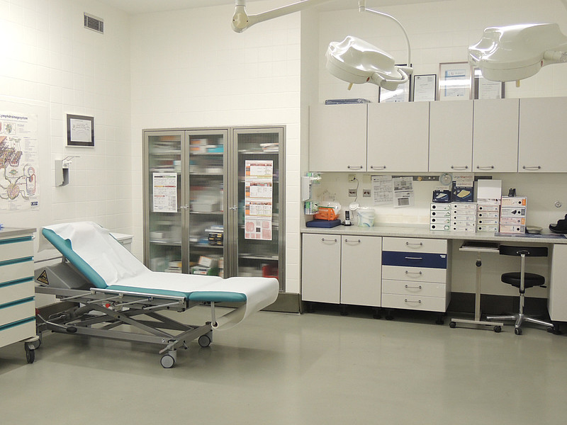 Krankenhausbehandlungsraum mit Bett, Medizinschränken und Beleuchtung, bereit für Patientenuntersuchungen.