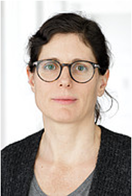 Porträt einer Frau mit Brille und dunklem Haar, die ein dunkles Oberteil trägt, vor einem neutralen Hintergrund.