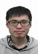 Person mit Brille und dunklen Haaren trägt grauen Hoodie, schaut geradeaus vor weißem Hintergrund.